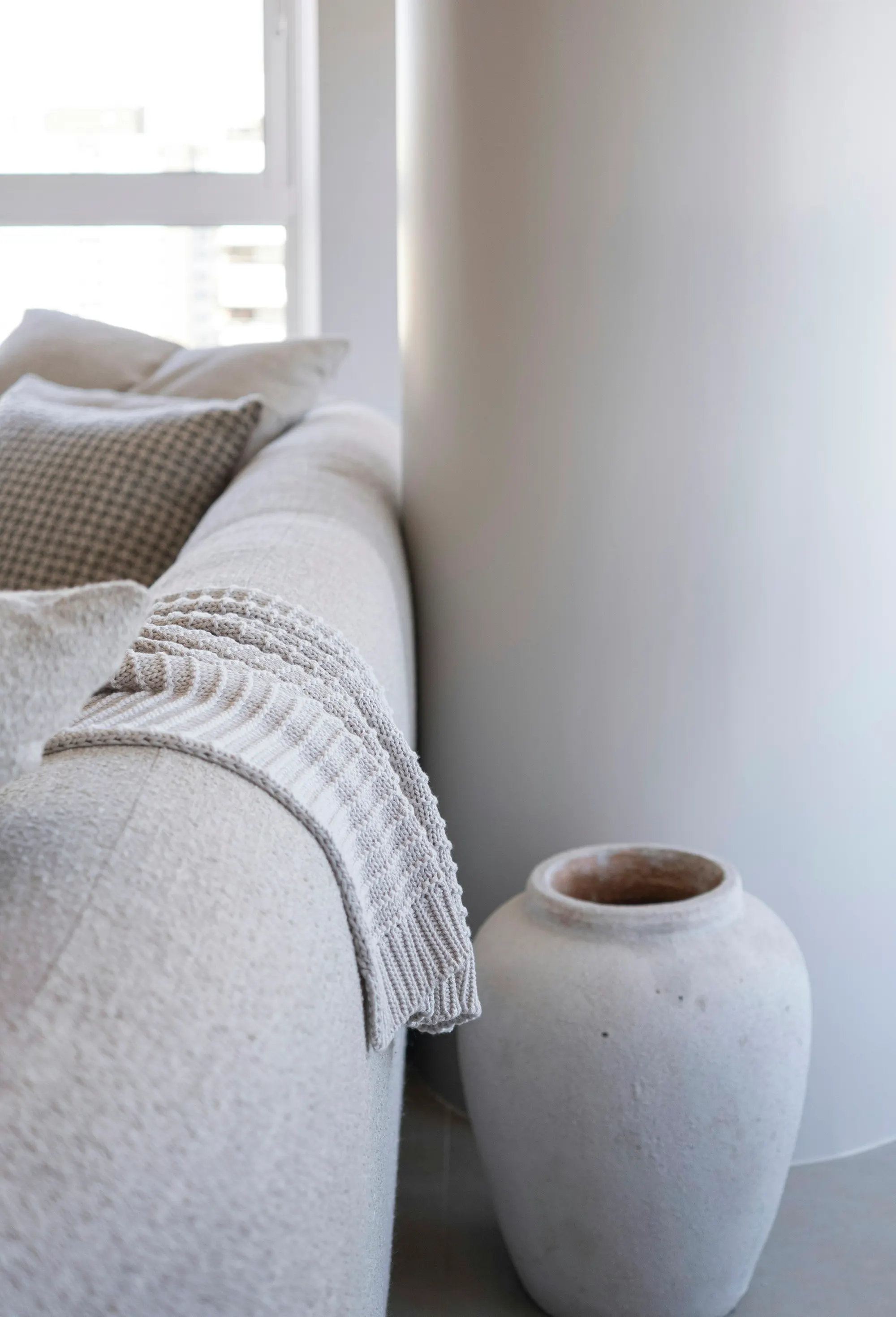A phone resting face down on a linen sofa beside a folded blanket